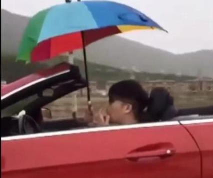 Man-holds-umbrella-while-driving-convertible-in-the-rain.jpg